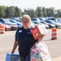 GVSU Alumna carries a box fan, comforter and pillows, and a toaster